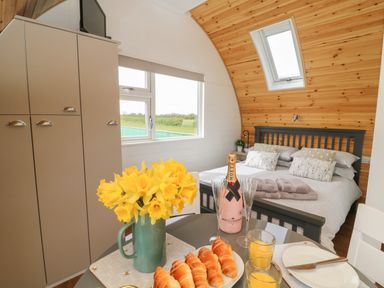 A bedroom with a bed and pillows a table with croissants orange juice flowers and champagne at Primrose Seaton near Hornsea