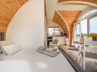 A bedroom with a bed pillows and towels a kitchen and dining area with chairs and a table at Primrose Seaton near Hornsea