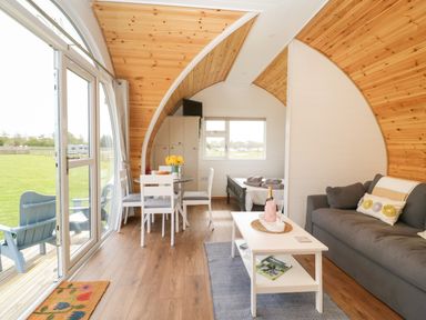 An open plan living area with a sofa coffee table dining table and a bed visible at Poppy Seaton near Hornsea