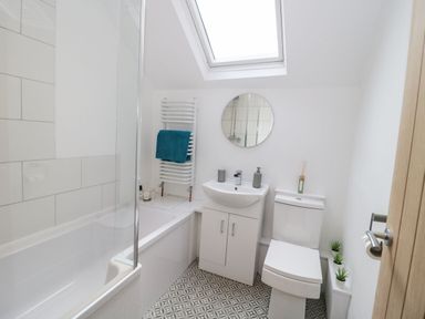 A bathroom with bathtub shower sink toilet and round mirror at Ty Capel Bach in Rachub