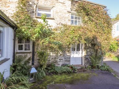 A stone cottage exterior with ivy growing around windows and door at Yanway Cottage in Troutbeck near Troutbeck Bridge
