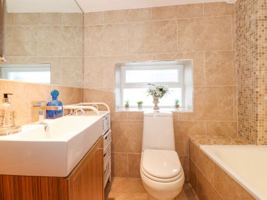 A bathroom with a white sink and a toilet under a window with flowers at Yanway Cottage in Troutbeck near Troutbeck Bridge