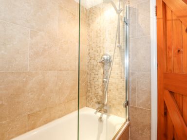 A bathroom with a bathtub shower and tiled walls at Yanway Cottage in Troutbeck near Troutbeck Bridge