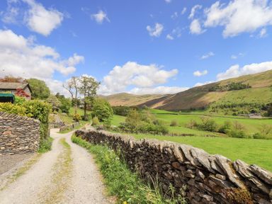 A country road with stone walls and green fields by hills at Yanway Cottage in Troutbeck near Troutbeck Bridge