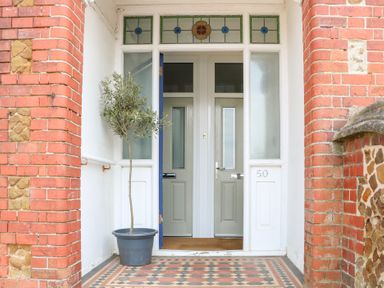 An entrance with a tiled floor a potted plant and two doors with stained glass windows above at Flat 1 Hunstanton