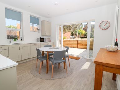 A kitchen with a round dining table and four chairs next to sliding glass doors leading to a garden at Flat 1 in Hunstanton