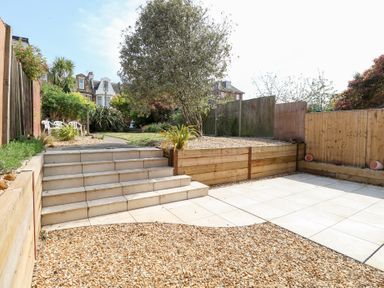 A garden with tiled steps leading to a lawn and gravel area at Flat 1 in Hunstanton