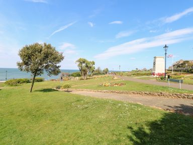 A park with grassy areas trees flower beds a walking path and a monument near the sea at Flat 1 Hunstanton