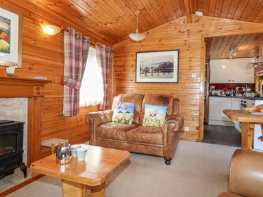 A living room with leather sofa and wooden coffee table near a fireplace at Robins Nest Number 12 Burnside Park near Keswick