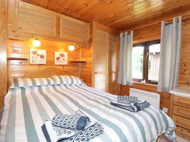 A bedroom with a double bed with striped bedding and towels on it at Robins Nest Number 12 Burnside Park near Keswick
