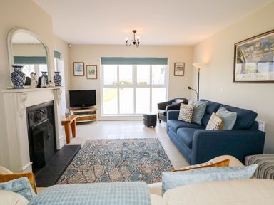 A living room with a blue sofa a fireplace and a rug at Stillwaters in Bushmills County Antrim