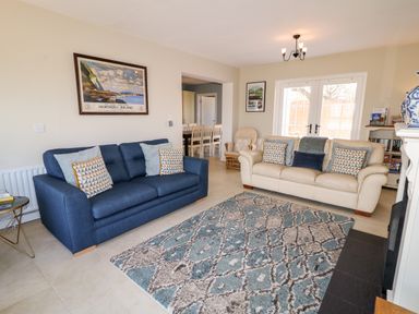 A living room with two sofas a patterned rug and framed artwork above at Stillwaters in Bushmills County Antrim