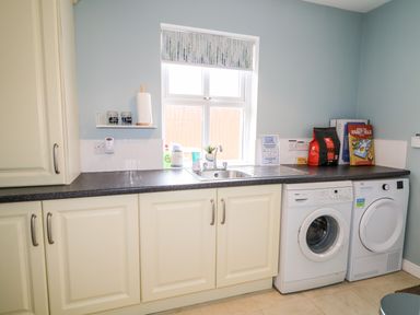 A laundry room with washing machine dryer sink and countertop at Stillwaters in Bushmills County Antrim
