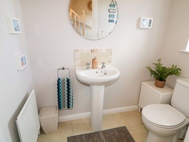 A bathroom with a pedestal sink mirror toilet towel and plant at Stillwaters Bushmills County Antrim