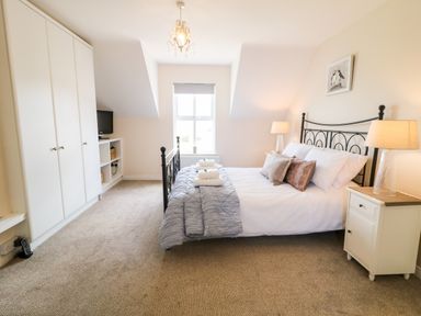 A bedroom with a bed lamps a wardrobe and a window at Stillwaters in Bushmills County Antrim