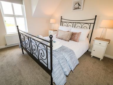 A bedroom with a black metal bed and bedside tables with lamps at Stillwaters in Bushmills County Antrim