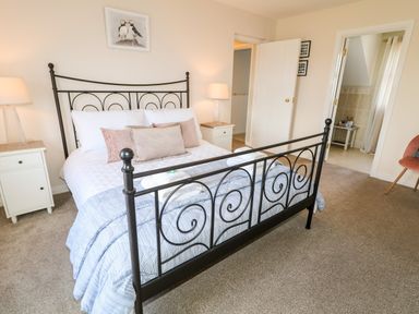 A bedroom with a metal bed frame two bedside tables with lamps and an open door showing a bathroom at Stillwaters in Bushmills County Antrim