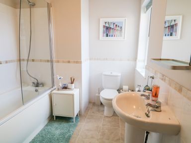 A bathroom with a bathtub shower toilet sink cabinet and a picture on the wall at Stillwaters in Bushmills County Antrim