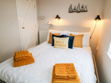 A bedroom with a bed with folded towels and pillows with hello sunshine text at Stillwaters in Bushmills County Antrim