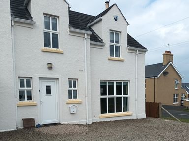 A white house with multiple windows a white door and gravel in front at Stillwaters in Bushmills County Antrim
