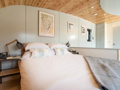 A bedroom with a bed framed by two bedside tables and lamps with framed pictures on the wall at Low Longlands in Cartmel