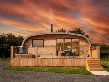 A wooden pod with a deck table and chairs and hot tub in front at Low Longlands in Cartmel