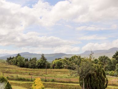 A rural landscape with grass fields and trees with hills in the background at Ty Coed - 63 Bronaber near Trawsfynydd