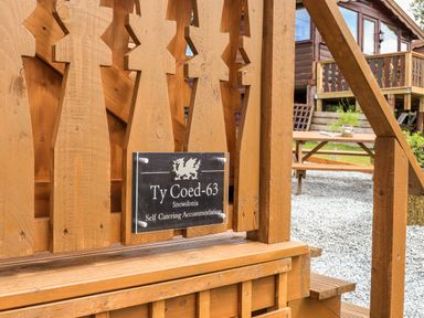 A wooden structure with a sign that reads Ty Coed 63 Snowdonia Self Catering Accommodation and a picnic table outside at Ty Coed 63 in Bronaber near Trawsfynydd