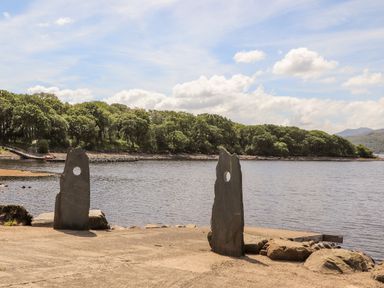 Two stone slabs with holes near a body of water with trees in the background at Ty Coed - 63 in Bronaber near Trawsfynydd