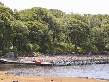 A lake with small boats docked at a pier and trees in the background at Ty Coed - 63 in Bronaber near Trawsfynydd