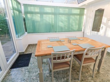 A dining area with a wooden table and four chairs in a room with green vertical blinds at Dunes View in Cubert