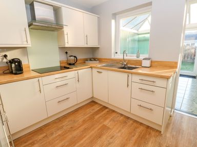 A kitchen with white cabinets wooden countertops a sink under a window and appliances at Dunes View in Cubert