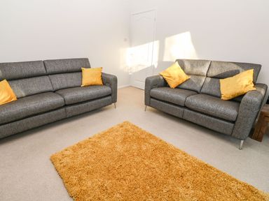 A room with two grey sofas with yellow pillows and a yellow rug on the floor at Dunes View in Cubert