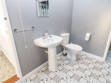 A bathroom with a toilet sink mirror and patterned tile floor at Dunes View in Cubert