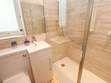 A bathroom with a shower enclosure a sink with cabinet and a window at Dunes View in Cubert