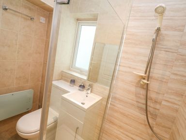 A bathroom with a toilet sink mirror and shower at Dunes View in Cubert