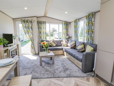 A living room with a grey sectional sofa and a coffee table with flowers at Jean's Place in East Heslerton near West Heslerton
