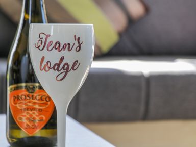 A white wine glass with Jean's lodge written on it and a bottle of prosecco in the background at Jean's Place in East Heslerton near West Heslerton