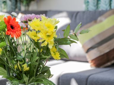 A bouquet of colorful flowers in a vase on a table with a sofa and cushions in the background at Jeans Place in East Heslerton near West Heslerton