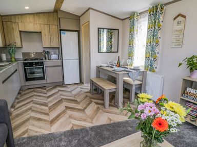 A kitchen and dining area with wooden cabinets and table with flowers in a vase at Jeans Place in East Heslerton near West Heslerton
