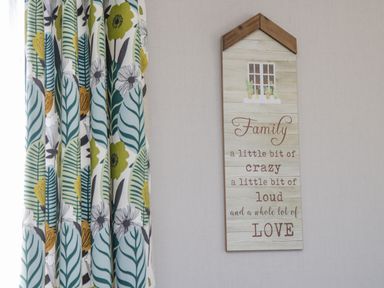 A decorative wall plaque with a family quote next to patterned floral curtains at Jeans Place East Heslerton near West Heslerton