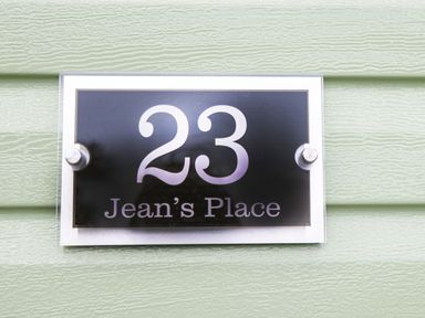 A house number sign 23 Jean's Place on a green textured wall at Jean's Place in East Heslerton near West Heslerton