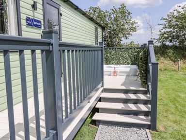 Stairs leading to a deck with a hot tub and a bottle with glasses on the deck at Jeans Place in East Heslerton near West Heslerton