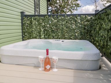 An outdoor hot tub with a bottle of prosecco and two white glasses on a wooden deck at Jeans Place in East Heslerton near West Heslerton