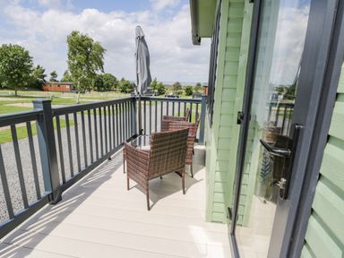 An outdoor balcony with four wicker chairs and a table with a closed umbrella at Jean's Place in East Heslerton near West Heslerton