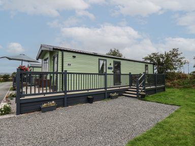 A green mobile home with gray railing and steps on a gravel and grass area at Jean's Place in East Heslerton near West Heslerton