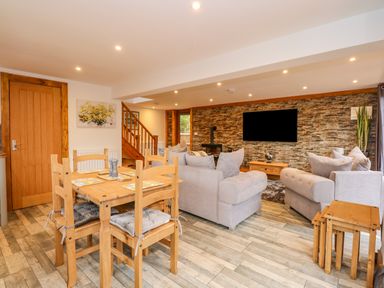 An open living and dining area with wooden furniture and gray sofas at Little Lodge in Pentney near King's Lynn