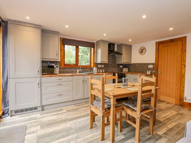 A kitchen with wooden dining table and chairs and grey cabinets at Little Lodge in Pentney near King's Lynn