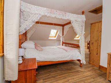 A bedroom with a wooden four poster bed with lace curtains wooden furniture and skylight windows at Little Lodge in Pentney near King's Lynn