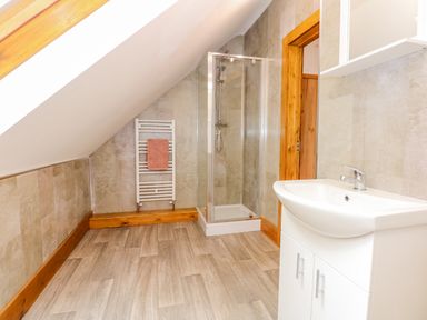 A bathroom with a shower cubicle a sink with cabinet and a towel rack with a towel at Little Lodge in Pentney near King's Lynn